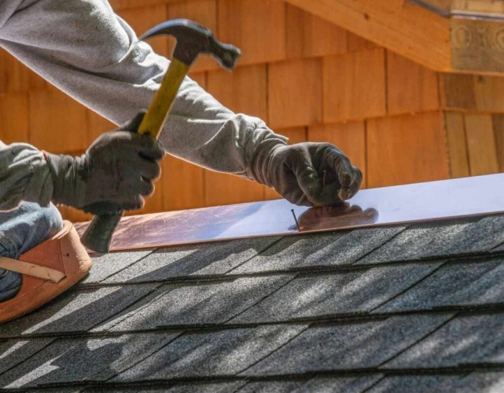 Hampton VA residential roofing worker installing copper flashing on shingle roof.