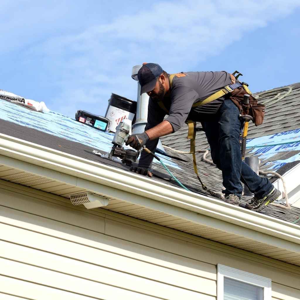 Flat roof repair Suffolk, VA man installing asphalt shingles for roof replacement.